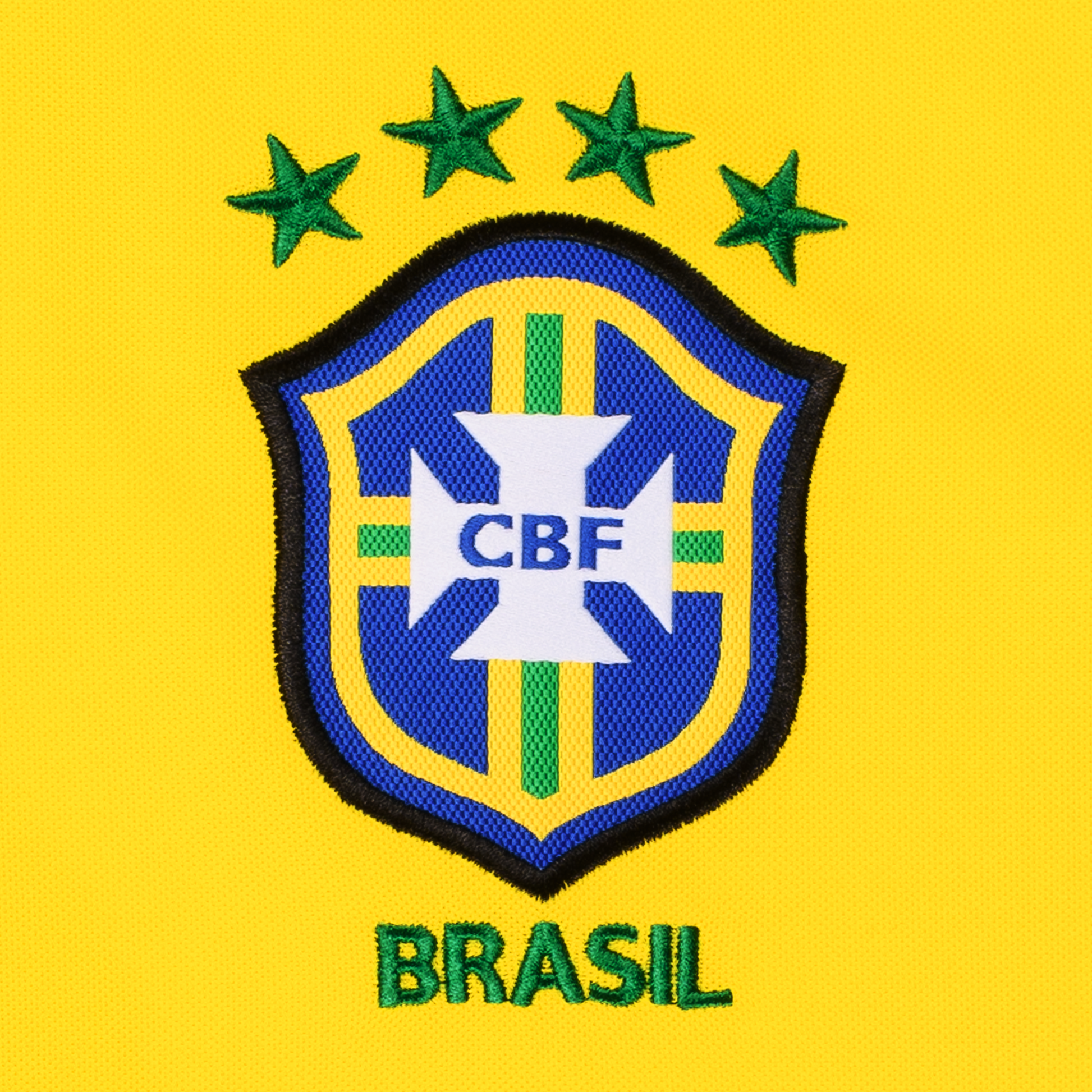 Gewebtes Verbands-Logo des brasilianischen Fußballverbandes CBF Confederação Brasileira de Futebol vor gelbem Hintergrund mit grün gesticktem Schriftzug BRASIL und vier Sternen für vier gewonnene Weltmeisterschaften auf der Vorderseite des Heim-Trikots der brasilianischen Nationalmannschaft zu Fußball-WM 1998